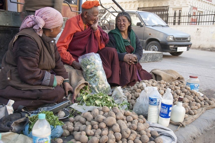 Ladakhi women sell potatoes and milk on sidewalk of street