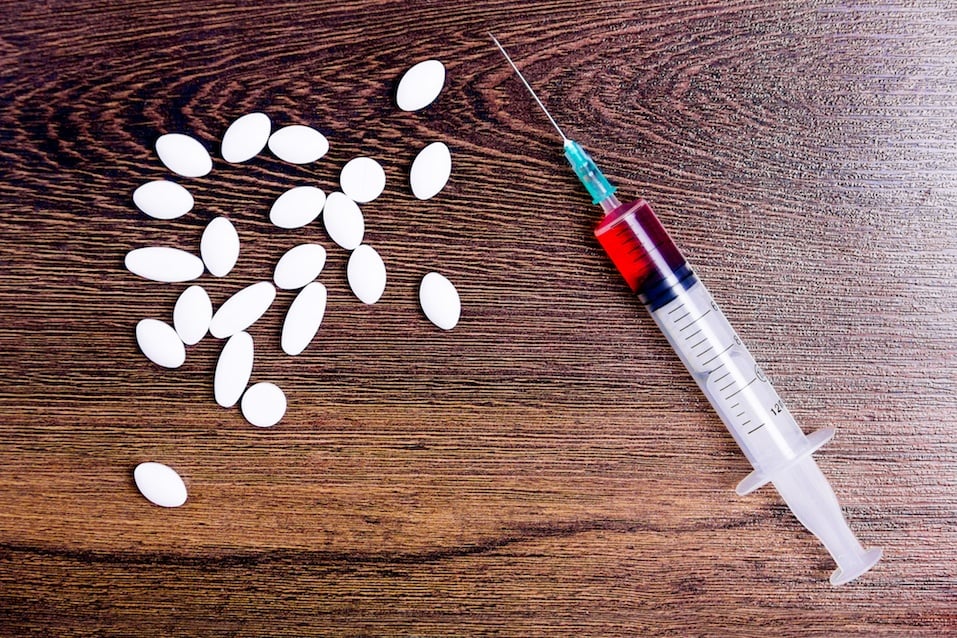 Pharmaceutical medicament. White pills and syringe filled with cure isolated on wooden background