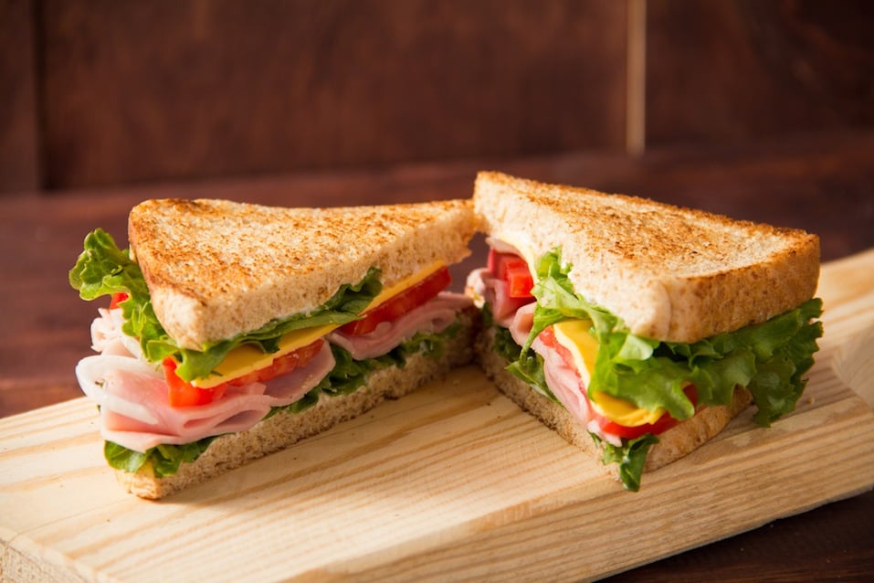 Sandwich tomato, lettuce, onion and yellow cheese on a wooden table