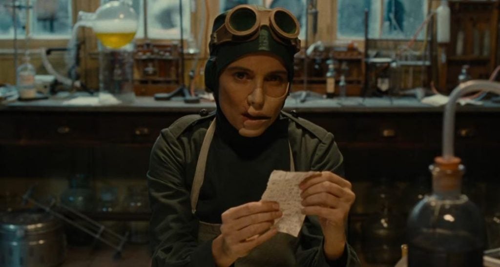 Doctor Poison, wearing a medical apron and goggles, holding a piece of paper