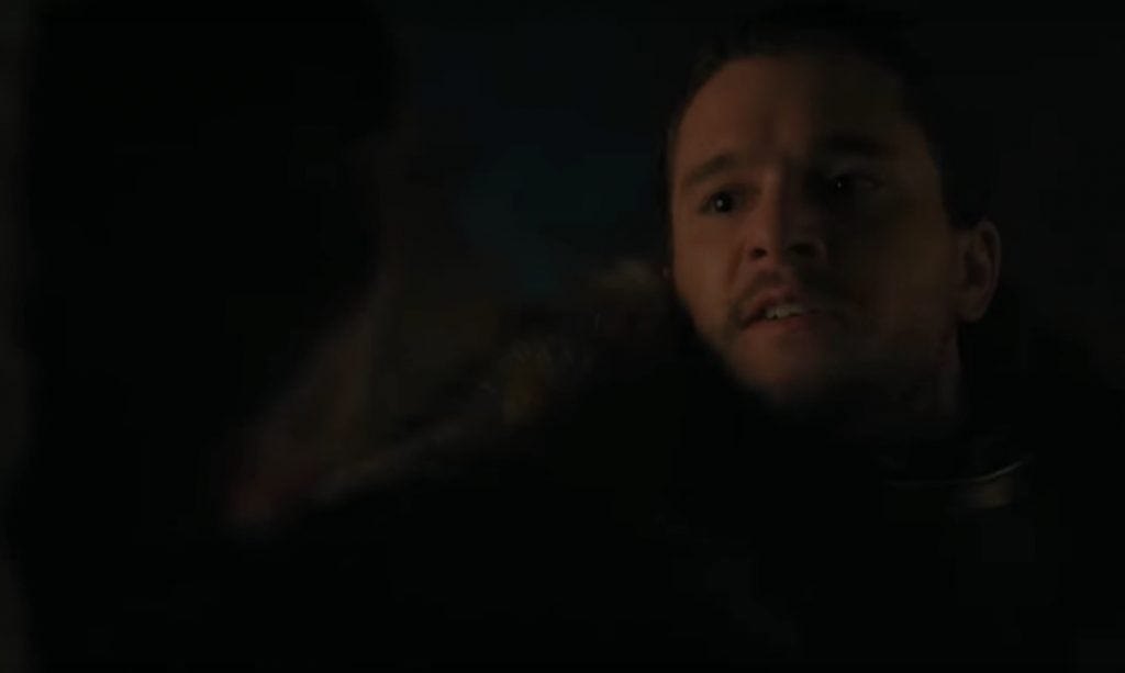 Jon Snow pushes an unseen man up against a wall in the dark