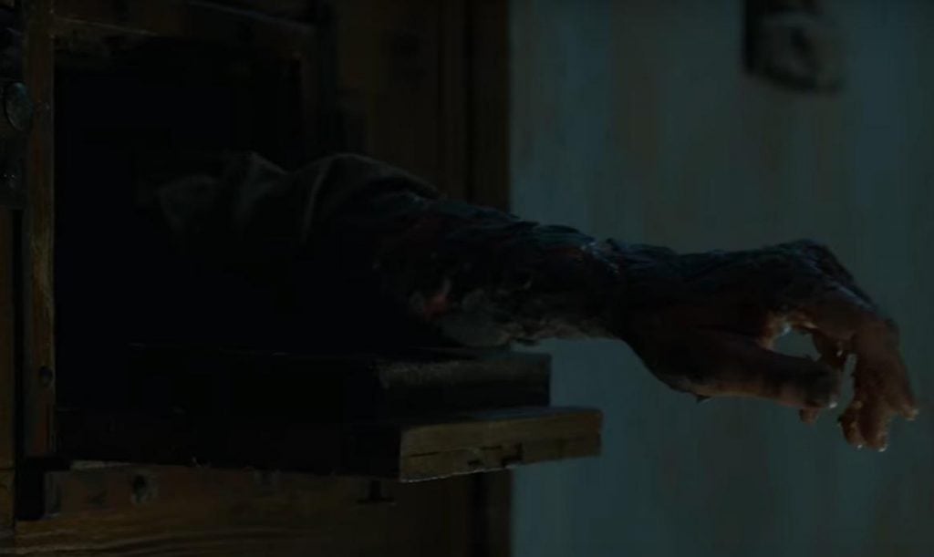 An arm extended out a small window in a dungeoun