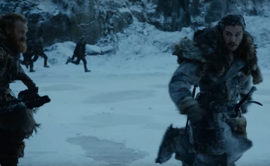 Jon Snow wearing furs, looking startled, and running to the right of the frame in the snow