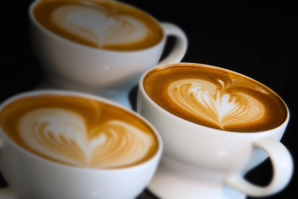 three lattes with foam poured into hearts Starbucks latte