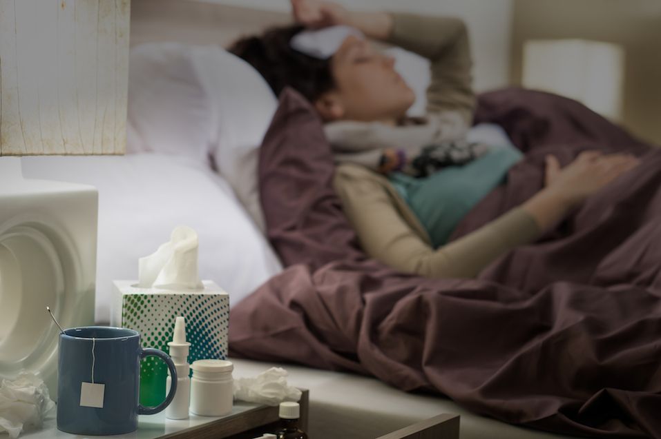 Tissue, flu medicines and tea on bedside table sick woman