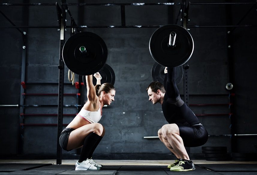 Young man and woman holding huge heavy barbells