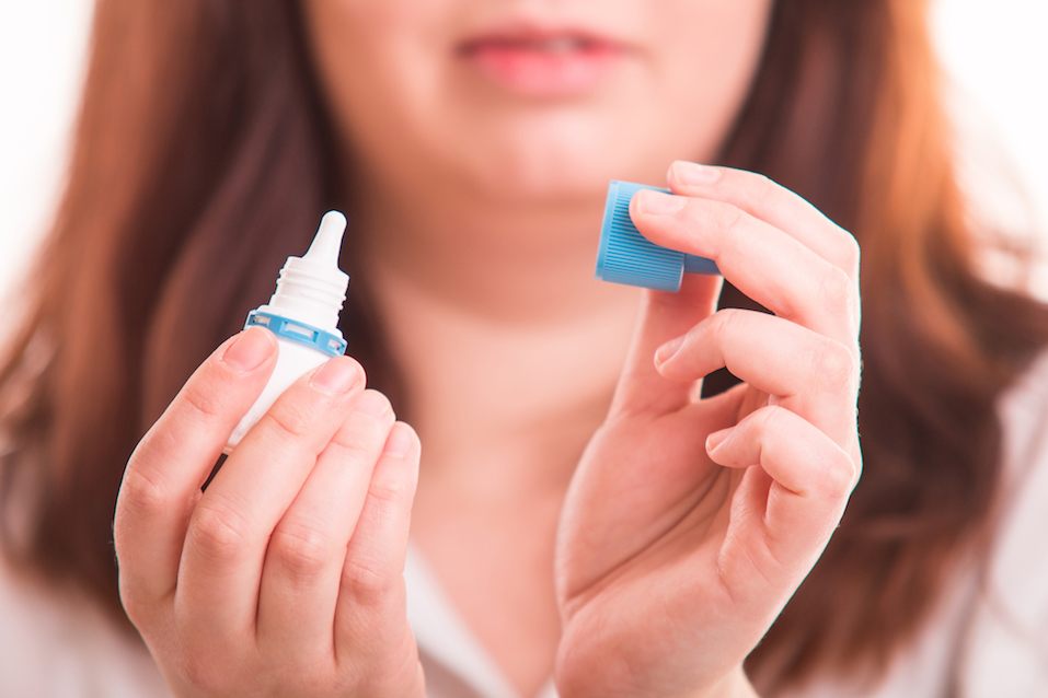 Woman holding eye drops in her hand