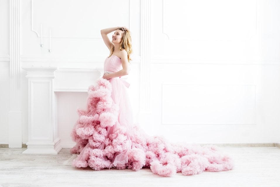 Woman portrait in a long pink dress on white