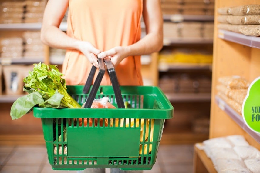 young woman holding a basket full of groceries