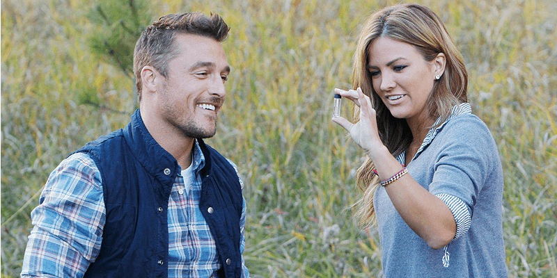 Chris Soules and a woman are looking at a tube while in a field.