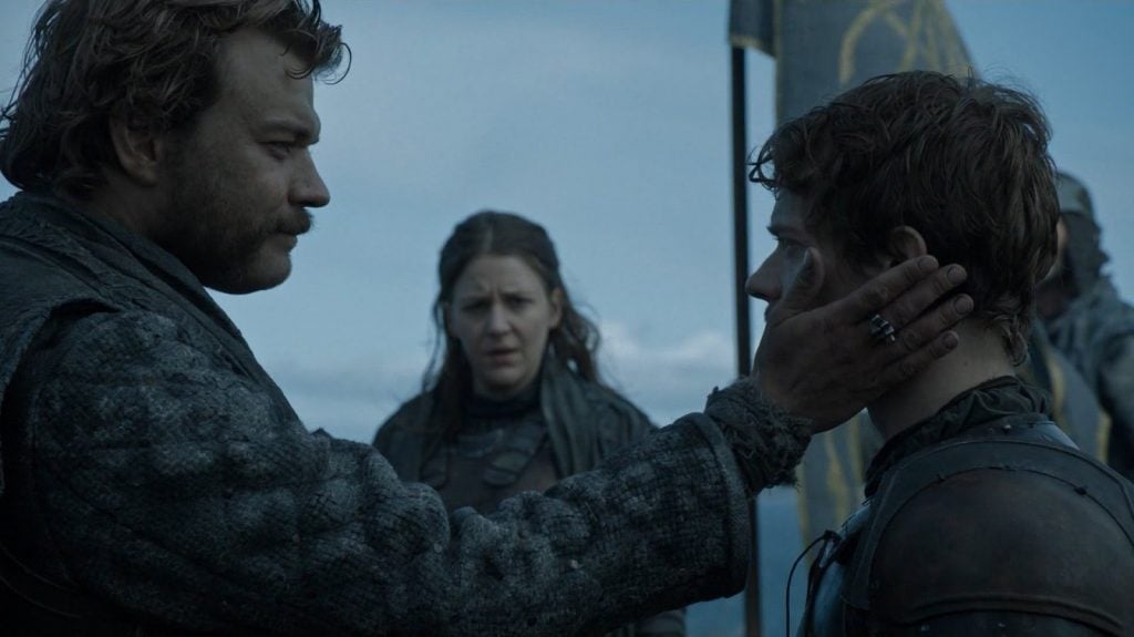 Euron holds Theon's head in his hands, as the two look intensely at each other on a cliff above a beach Euron holds Theon's head in his hands, as the two look intensely at each other on a cliff above a beach