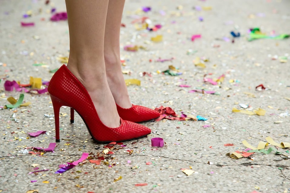 female legs in red shoes against the confetti and garlands - selective focus, copy space
