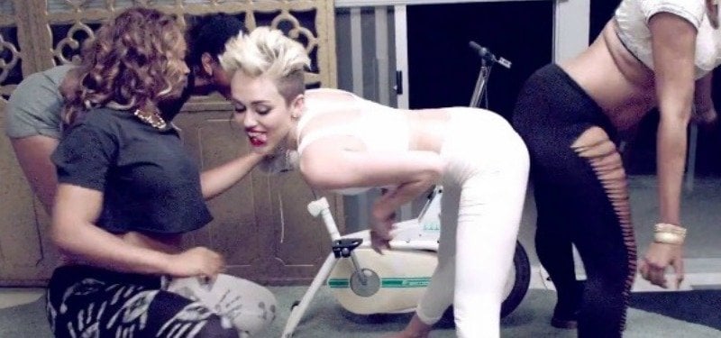 Miley Cyrus is twerking as women are twerking behind her.