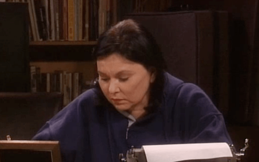 Roseanne sits at her desk with a typewriter