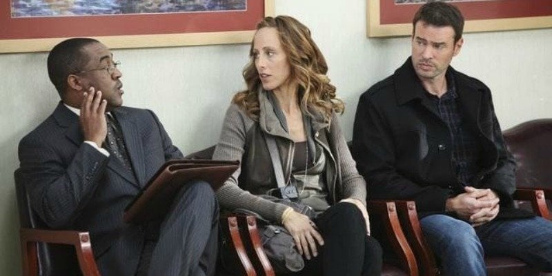 Scott Foley's character along with two other characters are sitting next to each other talking in a waiting room.