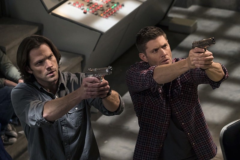 Sam and Dean aiming guns at an enemy.