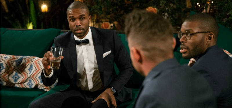 DeMario is talking to two other men and they are all wearing suits.