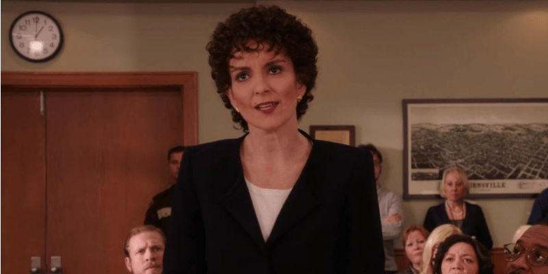 Tina Fey has a short and curly hair cut and is acting as a lawyer in a court room.