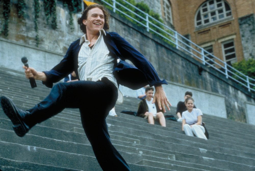 Heath Ledger, kicking his leg out in the bleachers of a football stadium and laughing