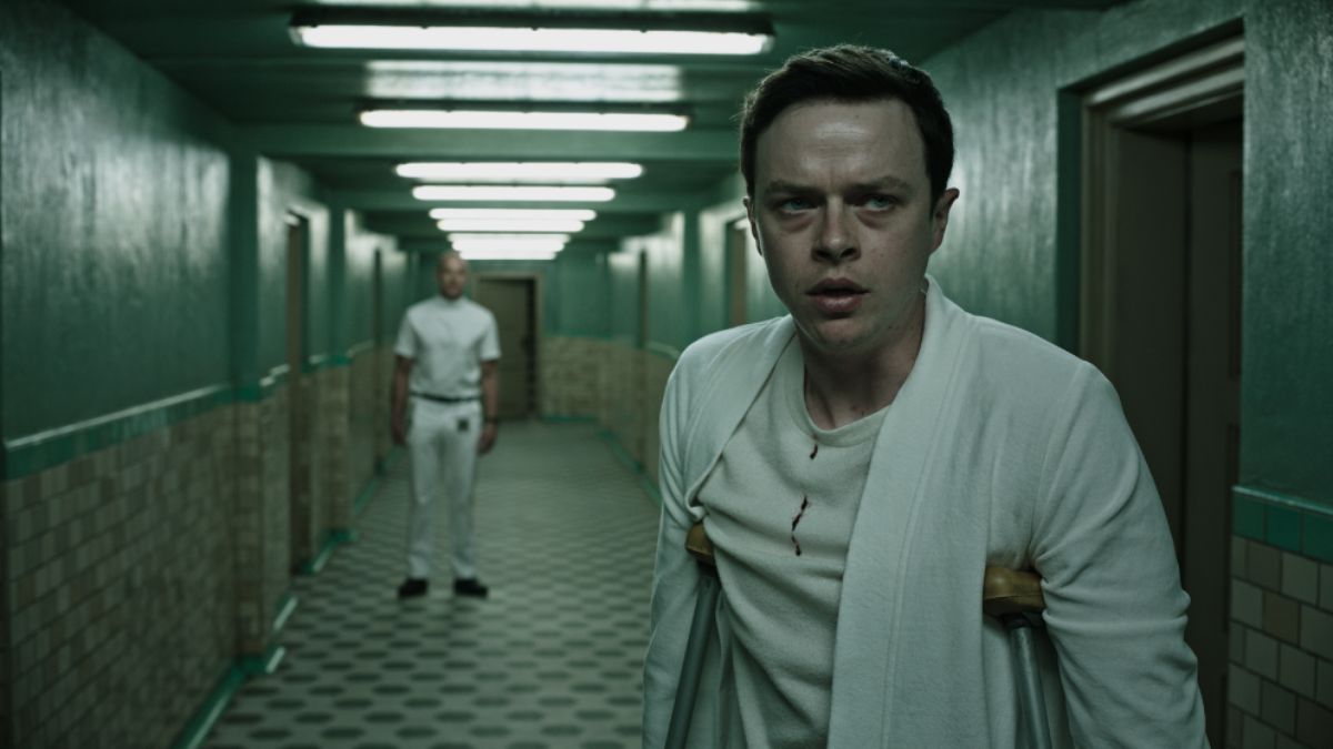Dane DeHaan stands on crutches in a hallway in A Cure for Wellness