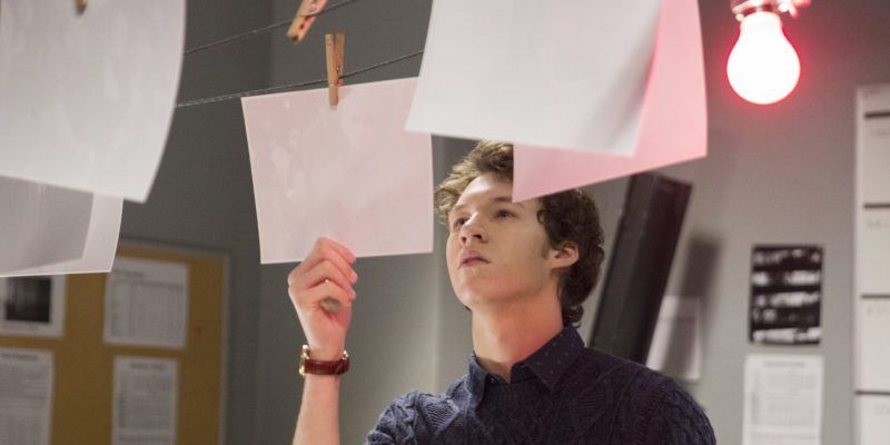 Tyler looks at photos in a darkroom in 13 Reasons Why