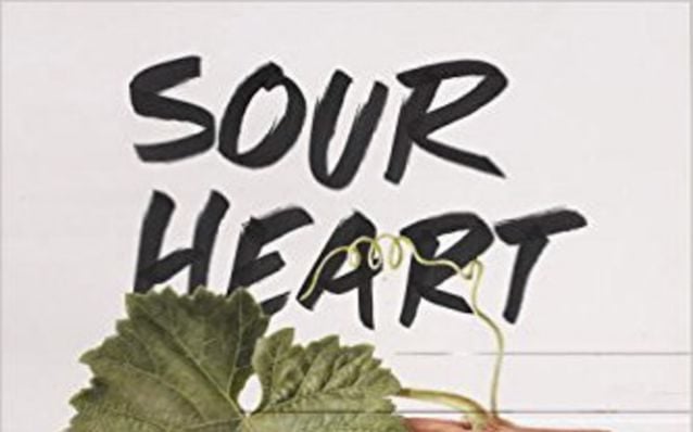 A bunch of grapes rest on a white table on the cover of Sour Heart