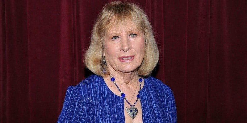 Christina Crawford is smiling in a blue outfit.