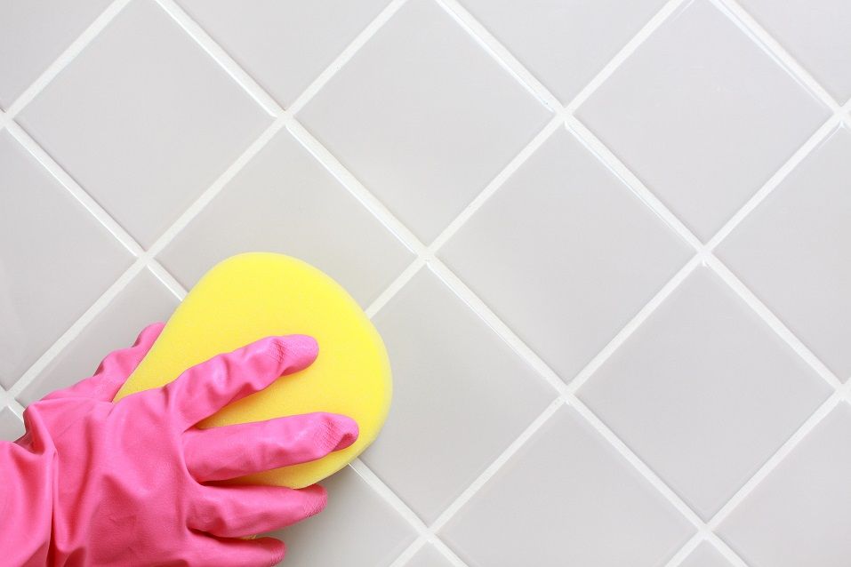 hand in pink glove cleaning the bathroom tiles
