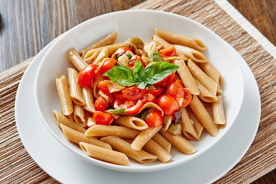 Close-up of pasta penne with cherry tomatoes on white plate Close-up of pasta penne with cherry tomatoes on white plate surrounded by ingredients - vegan food