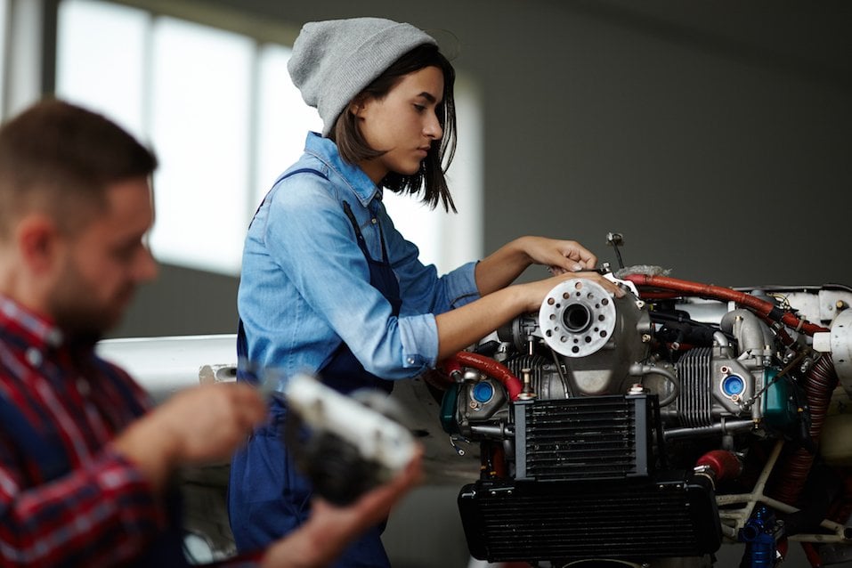  woman repairing engine parts in workshop