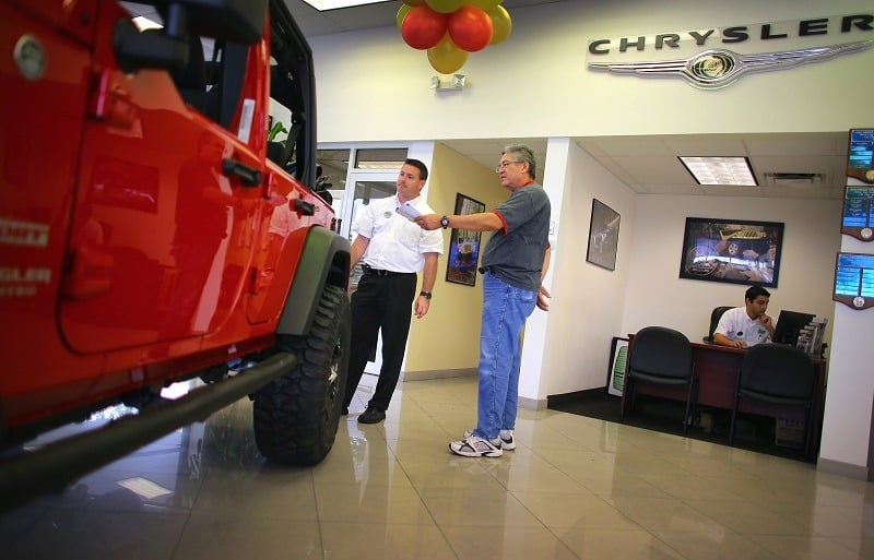 HOLLYWOOD, FL - OCTOBER 02: Chrysler sales consultant Doug Desloover (L) shows a Jeep Wrangler to Lewis Colon at the Hollywood Chrysler Jeep car dealership on October 2, 2012 in Hollywood, Florida. Chrysler Group LLC reported that its sales last month rose 12% from a year ago for its best September since pre-recession 2007.