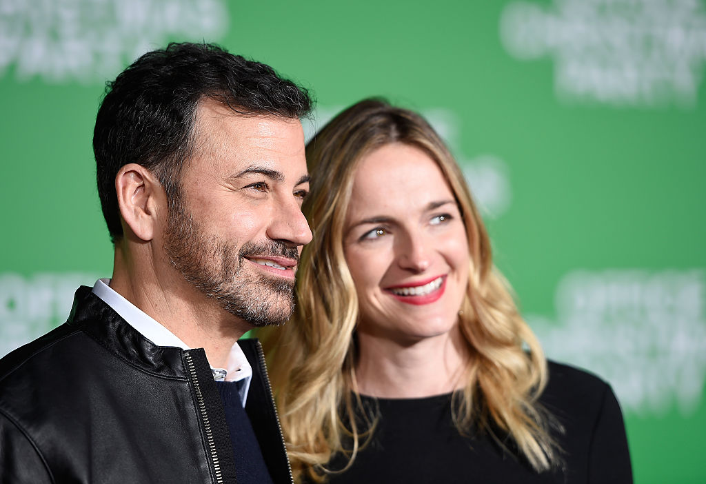 Jimmy Kimmel and Molly McNearney smiling on the red carpet together, looking off to the right of the frame