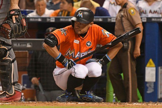The baseball player kneels down while holding his baseball bat. The baseball player kneels down while holding his baseball bat.