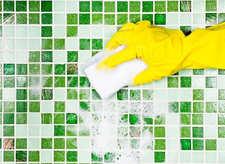 hand in yellow glove using sponge on tile