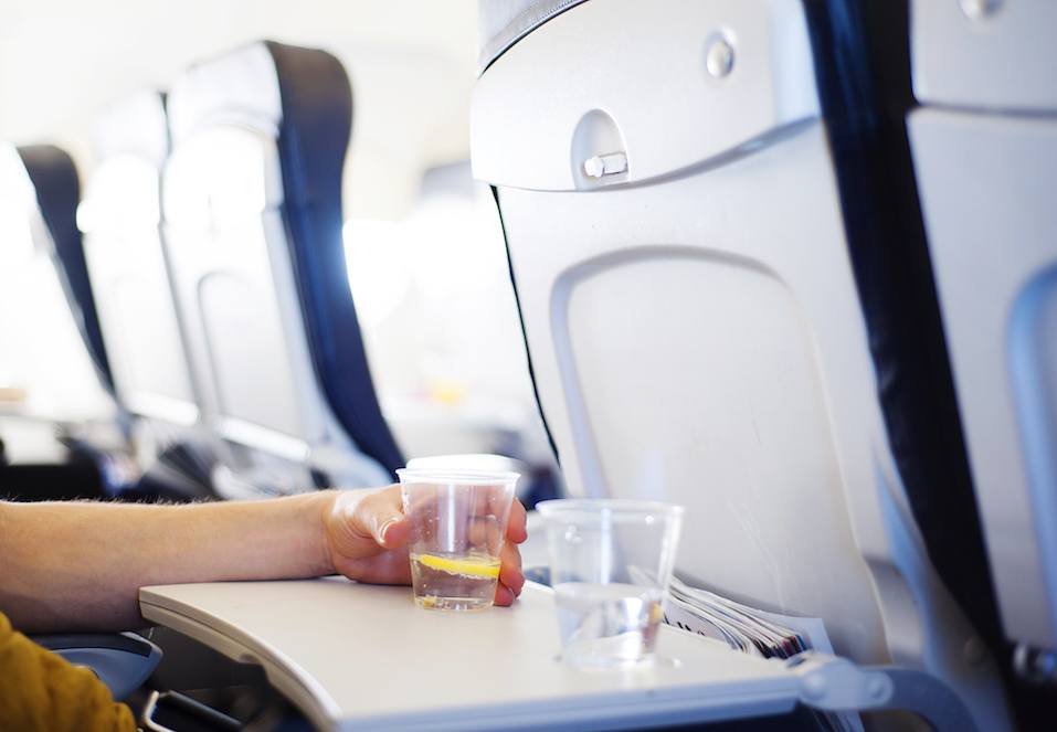 Happy man seating in the aircraft and drinking water