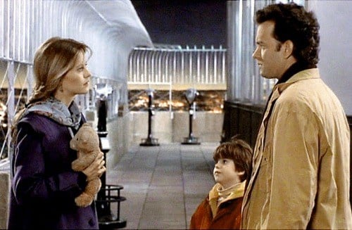 Tom Hanks stands next to a young child while talking to Meg Ryan in Sleepless in Seattle