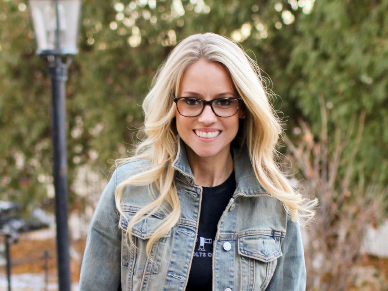 Nicole Curtis stands outside and smiles in a denim jacket.