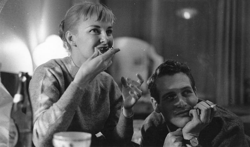 Joanne Woodward is eating while Paul Newman is next to her.