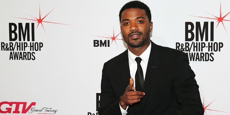 Ray J is posing in a suit and pointing on the red carpet.