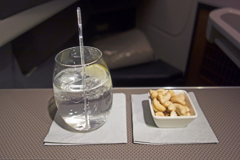 refreshing cocktail with lemon and ice and a dish of delicious hot chew nuts