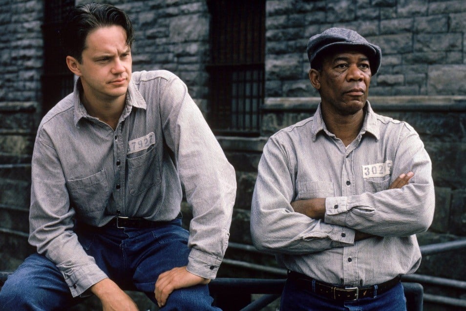 Tim Robbins and Morgan Freeman, sitting and standing respectively, looking off into the distance to the right of the frame