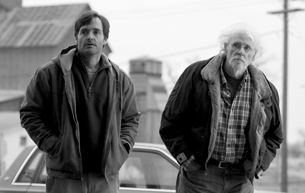 Will Forte and Bruce Dern, wearing heavy jackets and standing in a small town street, looking off-camera