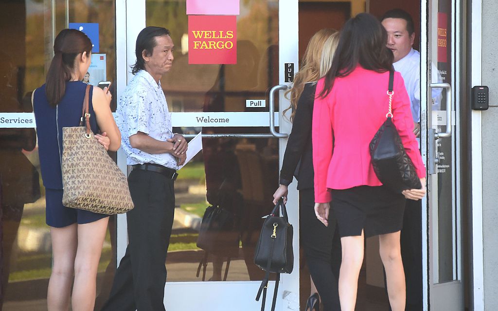 Customers await entry at a branch of Wells Fargo