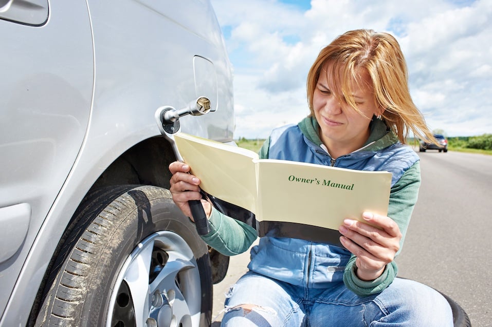 Woman reading owner's manual of her car