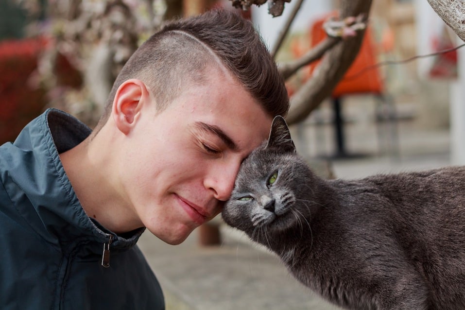 Young man befriending a cat on the streets in Tuscany