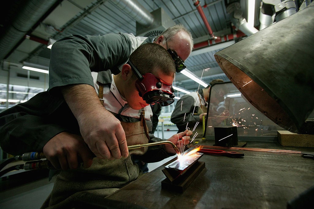 A foreman instructs a trainee in welding at training center offering apprenticeships
