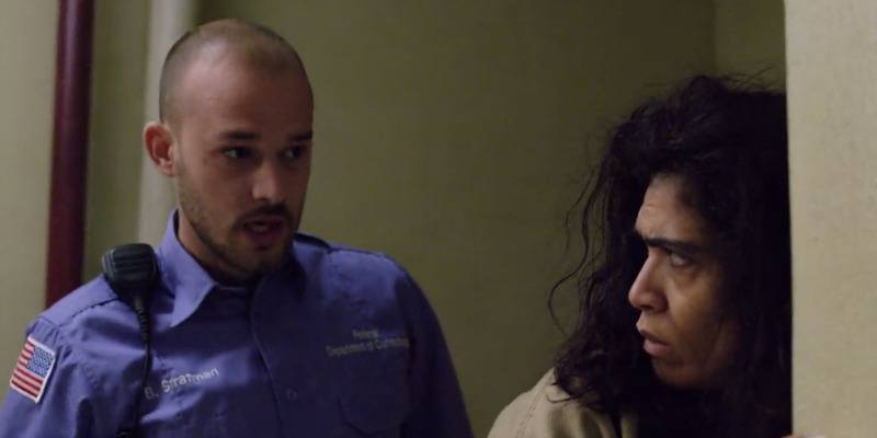 Blanca is being frisked and is looking back at the correctional officer.