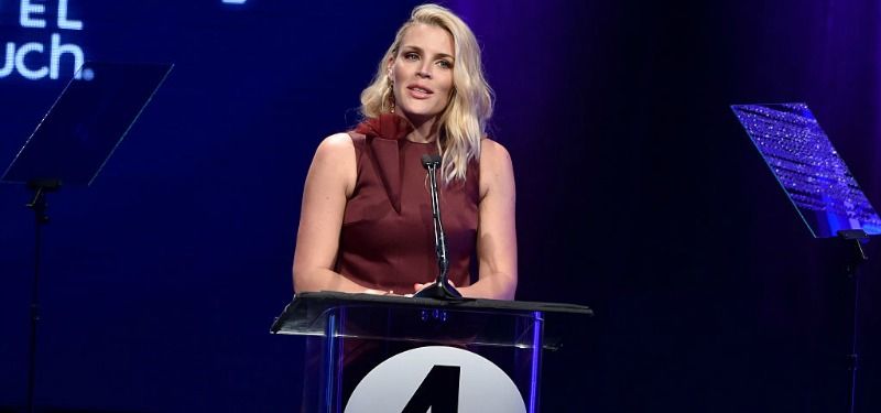 Busy Philipps is on stage standing at a podium.