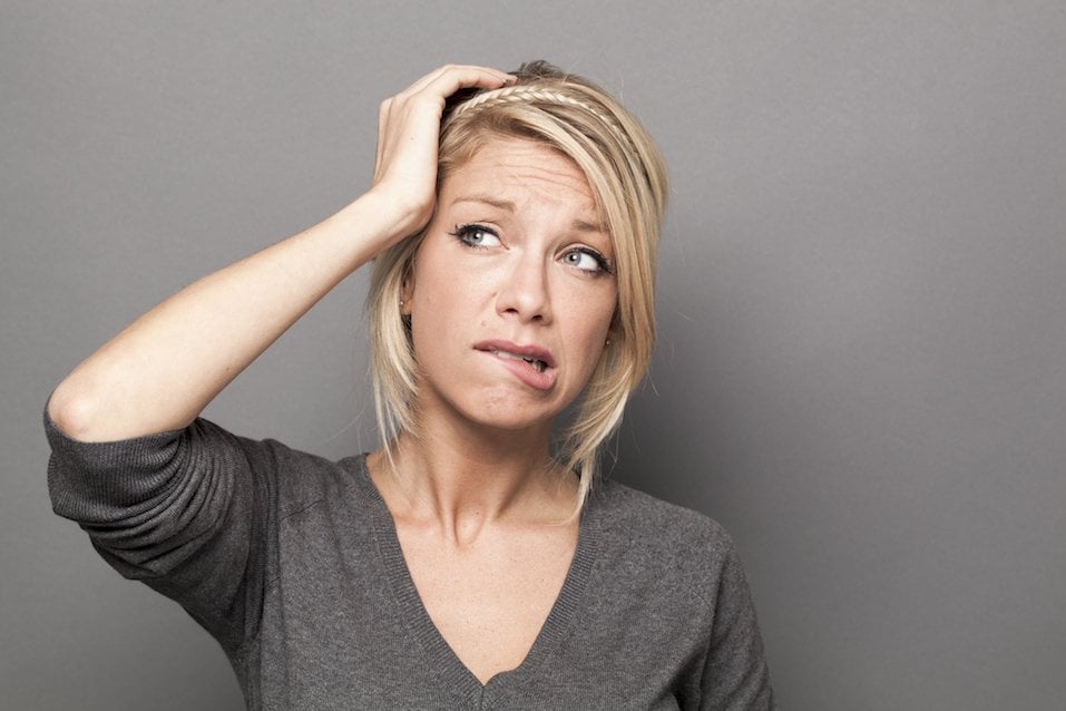 Woman who is holding her head and looking worried