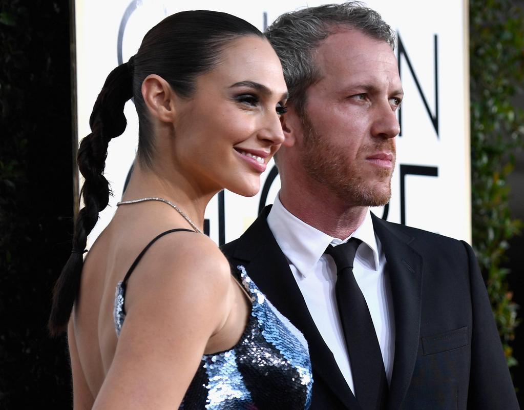 Gal Gadot in a blue dress, smiling on the red carpet with Yaron Versano
